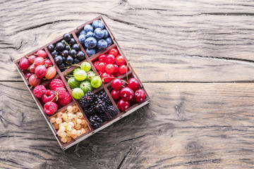 Colorful berries in wooden box on the table. Top view.