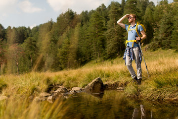 Young man crosses a mountain stream on a sunny day