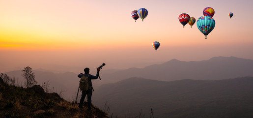 photographer celebrating success on top of a mountain in a majestic sunrise