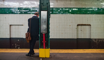 Young Business man at subway station stop waiting for the train.