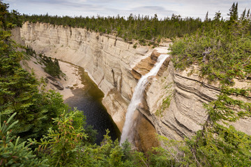 Horizontal side overview of tall Vaureal Fall and its canyon during a sunny summer day, Anticosti, Quebec, Canada