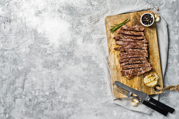 Sliced beef flank steak on wooden chopping Board. Gray background, top view, space for text