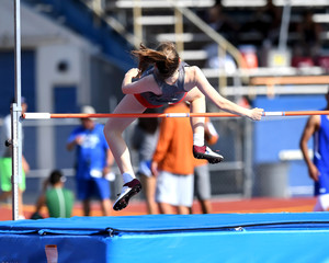 Young teenage girl competing in the high jump at a high school track meet