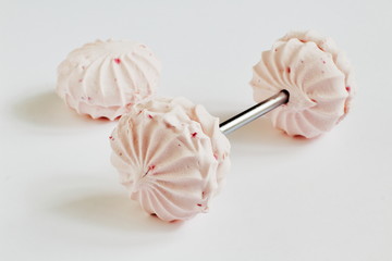 Original stylish barbell (dumbbell) from airy pink marshmallow and metal rod and marshmallow on light background. Symbolic concept — fitness, healthy lifestyle. Selective focus.