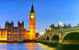 View of the Houses of Parliament and Westminster Bridge along River Thames in London at night.