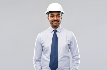 architecture, construction business and building - smiling indian architect or businessman in helmet over grey background