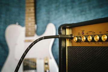 Guitar electric amplifier. Rock overdrive effect. Cable plugged into amp jack. Max volume control knob. Shallow depth of field