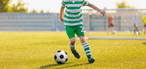 Kid kicking soccer ball. Close up action of boy soccer player running after ball, aged 8-10, playing a football match