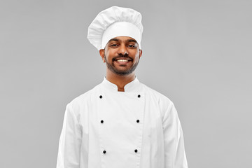 cooking, profession and people concept - happy male indian chef in toque over grey background