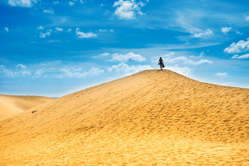 Desert landscape with woman on top of dune. Natural reserve Maspalomas Dunes, Gran Canaria, Spain