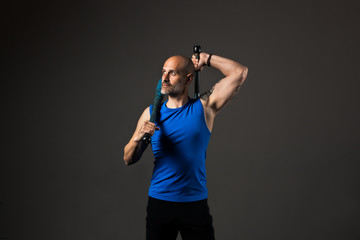 Athletic, middle aged man training with clubbells, studio background