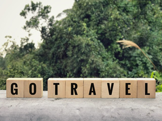 Motivational and inspirational wording - GO TRAVEL written on wooden blocks. Blurred styled background.