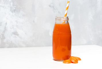 fresh carrot juice in a bottle on white background, closeup