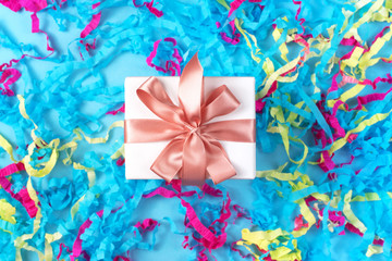 Gift box with colored streamers bright blue background top view of Flat lay