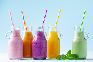 Summer colorful fruit smoothies in jars on blue background. Healthy, detox and diet food concept.