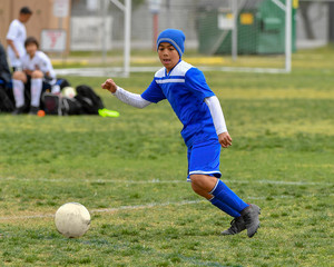 Young boy in blue uniform playing soccer