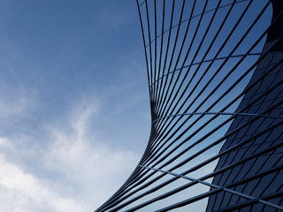 3D stimulate of high rise curve glass building and dark steel window system on blue clear sky background,Business concept of future architecture,lookup to the angle of the corner building.