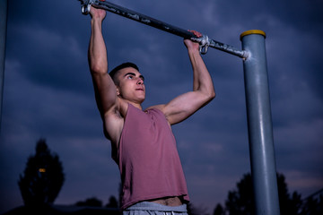 Young male athlete doing warm up and training in park during sunset.