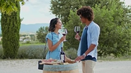 Romantic couple, man and woman toasting with red wine and eating appetizer at warm sunset.Medium shot. Friends italian trip in Umbria.4k slow motion