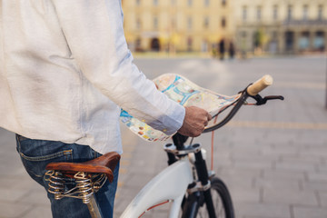 exploring the city with bicycle. man standing beside bicycle and holding street town map