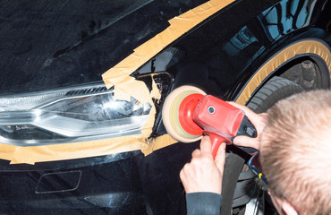 Professioneller Autolackierer poliert ein Fahrzeugteil mit der Poliermaschine - Serie Autowerkstatt