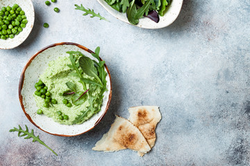 Green pea hummus spread or dip with mix salad leaves. Healthy raw summer appetizer, vegan, vegetarian snack. Copy space
