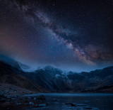 Composite image of Winter landscape of snowcapped Mountain Range at night with Milky Way above