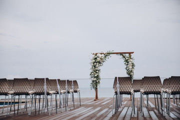 arch for the wedding ceremony and chairs for guests stand on the background of water