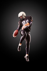 American football player in a jump with a ball on a black background