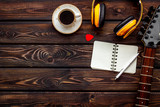 Musician work place with guitar, earphones, notebook and coffee on wooden background top view mock up