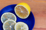 Composition with lemons on a wooden background. Lemons on a blue plate.Fresh yellow lemons, sliced into rings. A few slices of lemon on a wooden cutting board