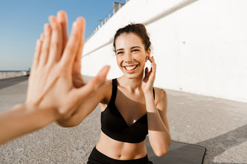 Cheerful young fitness woman giving high five