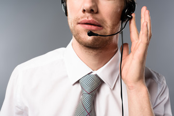 cropped view of serious call center operator touching headset