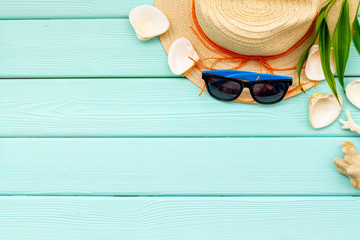 Straw hat, sun glasses, shells and plant for sea vacation on mint green wooden background top view mockup