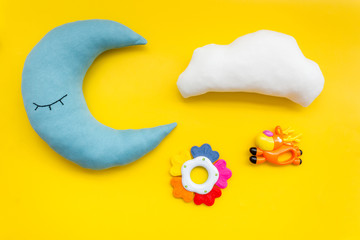 Moon pillow, clouds and toys for put baby in bed on yellow background top view