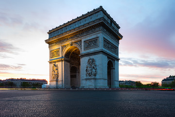 Paris street during sunrise with the Arc de Triomphe in Paris, France.
