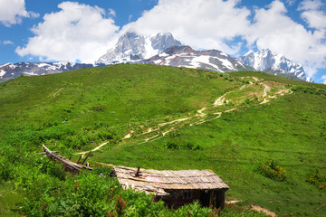 Svaneti mountains landscape with wooden house on green grassy highlands