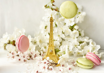 The Eiffel Tower figurine among white cherry flowers and sweet multicolored macaroons. Love, romance, spring.