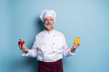 Food service, organic food, healthy diet, cooking and professional culinary concept - chef in white uniform holds vegetables.