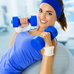 Young happy woman doing fitness exercise, at gym