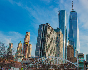 low angle view of white bridge, one world trade center, and financial district against blue sky
