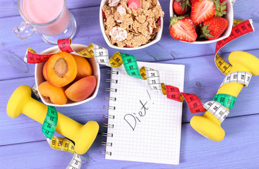 Healthy food, dumbbells, tape measure and notebook for notes. Slimming, healthy and sporty lifestyle
