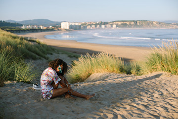 Young beautiful black woman relaxing at the beach on summer or spring vacation. San Juan de Nieva, Asturias, Spain.