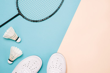 Shuttlecock and badminton racket with sport shoes on pastel color background