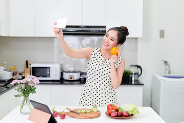 Young woman making selfie on smartphone at kitchen