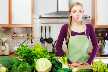 Woman housewife in kitchen with green vegetables