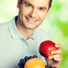 Happy smiling man with plate of fruits, outdoors