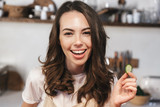 Cheerful young girl wearing apron sitting at the kitchen