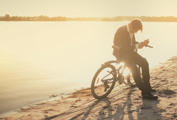 A man with a bicycle on a summer beach at sunset time