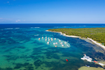 Aerial view on tropical beach with palm trees and speed boats shipping in caribbean sea